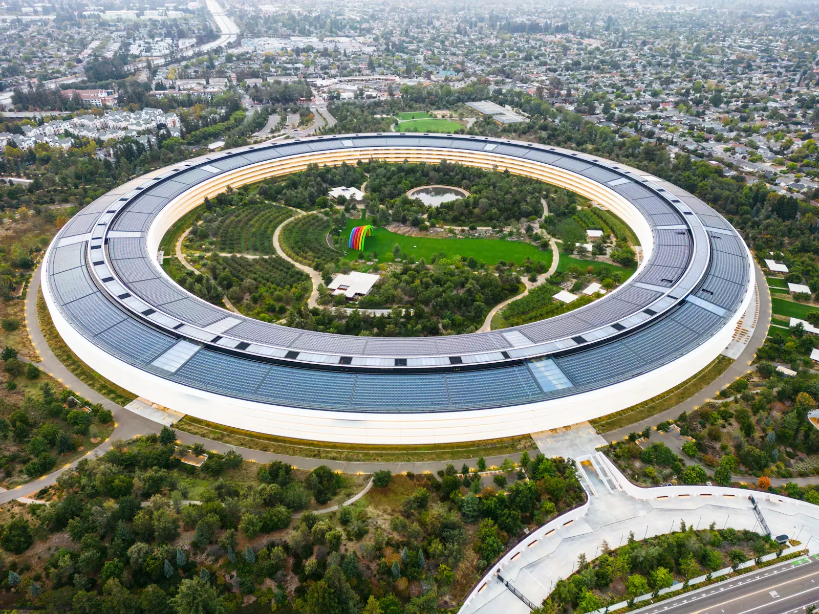 Aerial view of a ring-shaped corporate campus with a solar roof in Silicon Valley