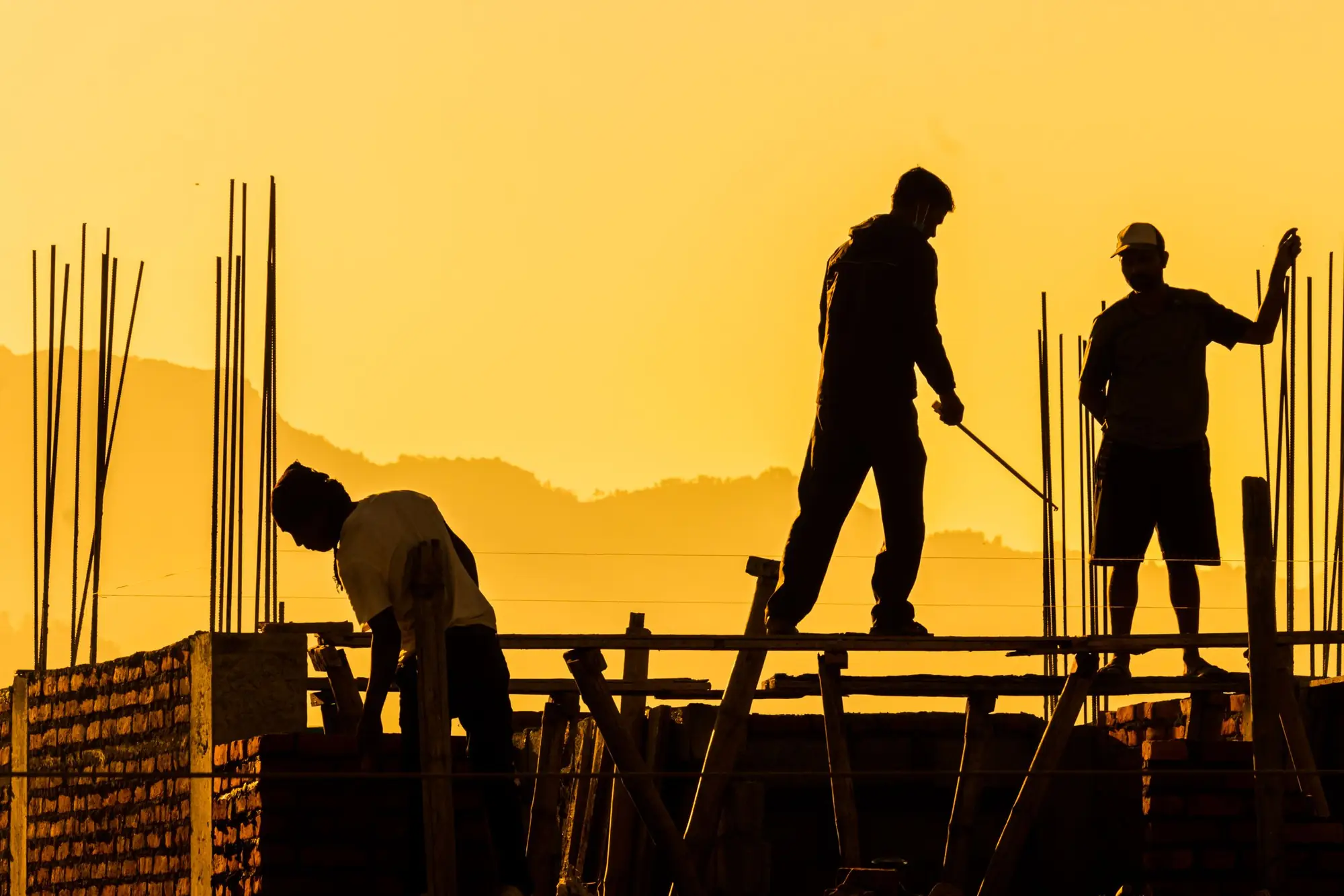 Construction workers silhouetted on a building frame at sunset