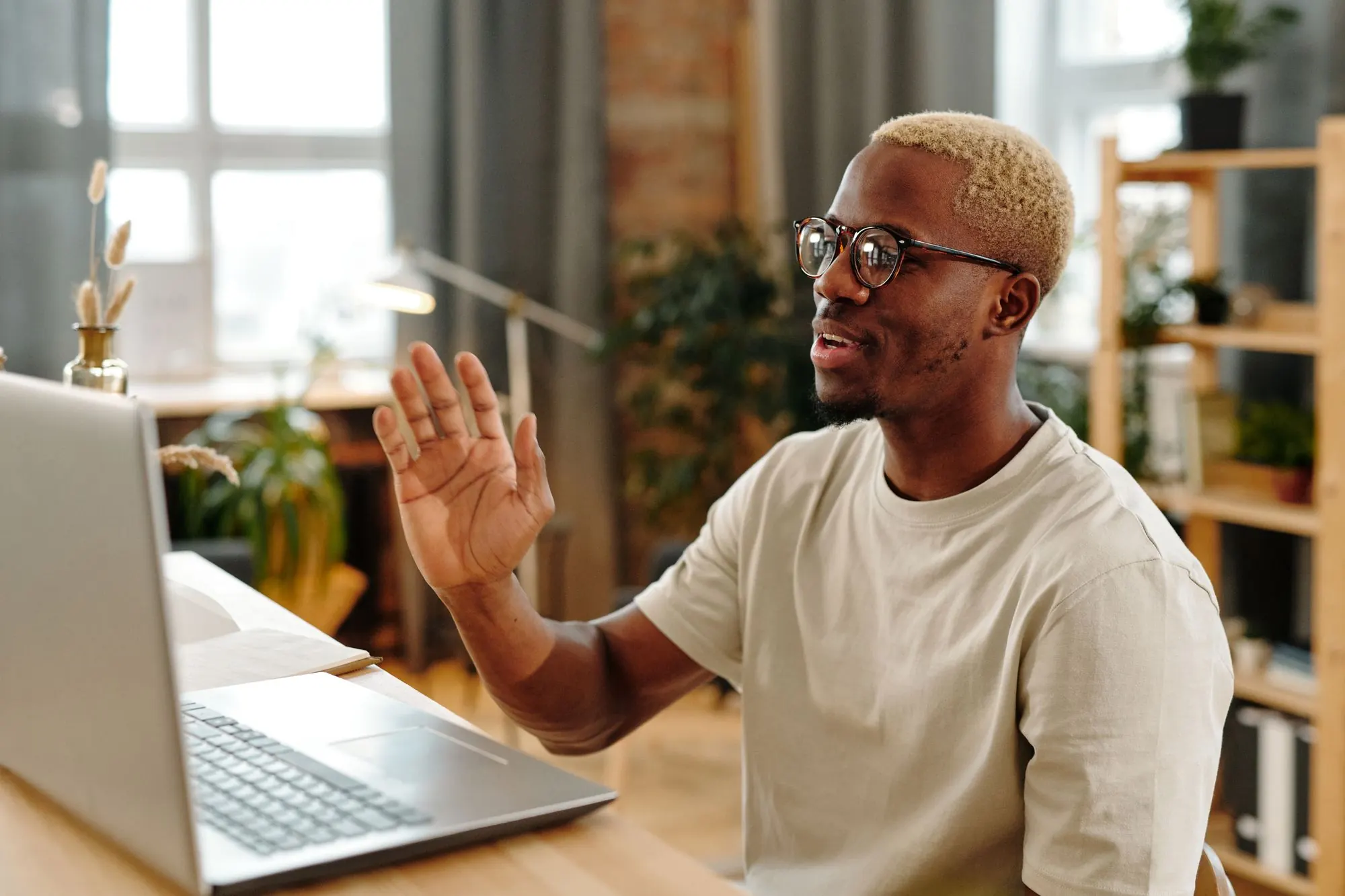 Man waving to a client on a laptop video call at home