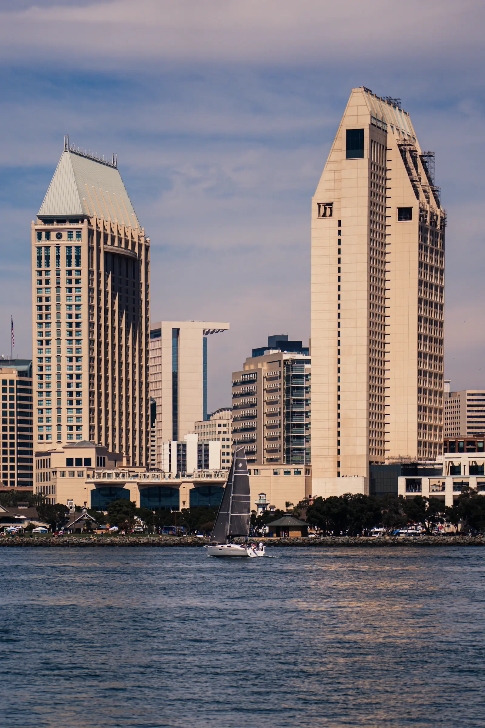 A sailboat crossing San Diego Bay in front of the downtown skyline
