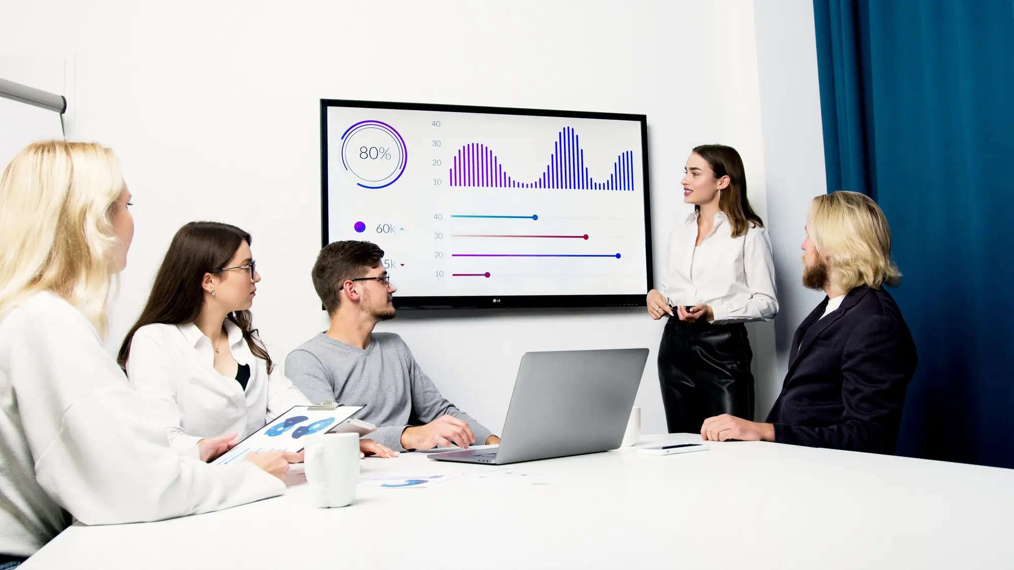 Team reviewing charts on a wall screen during a meeting